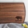A personalized wooden cutting board with an image of a cow.