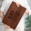 A woman holding up a wooden cutting board with the words eat scotch BBQ.