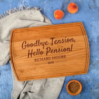 A personalized retirement gift, a wooden cutting board made of cherry wood with the words goodbye tension hello pension.