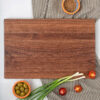 A wooden cutting board with olives and onions on it.