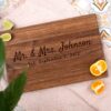 Custom walnut cutting board with the engraving Mr. & Mrs. Johson across the board and laying on top of a kitchen table.