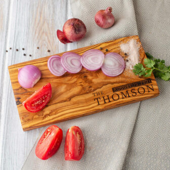 A wooden cutting board with tomatoes and onions on it.