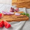 A Personalized wooden cutting board with tomatoes and onions on it.