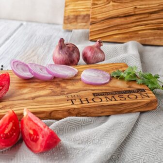 A Personalized wooden cutting board with tomatoes and onions on it.