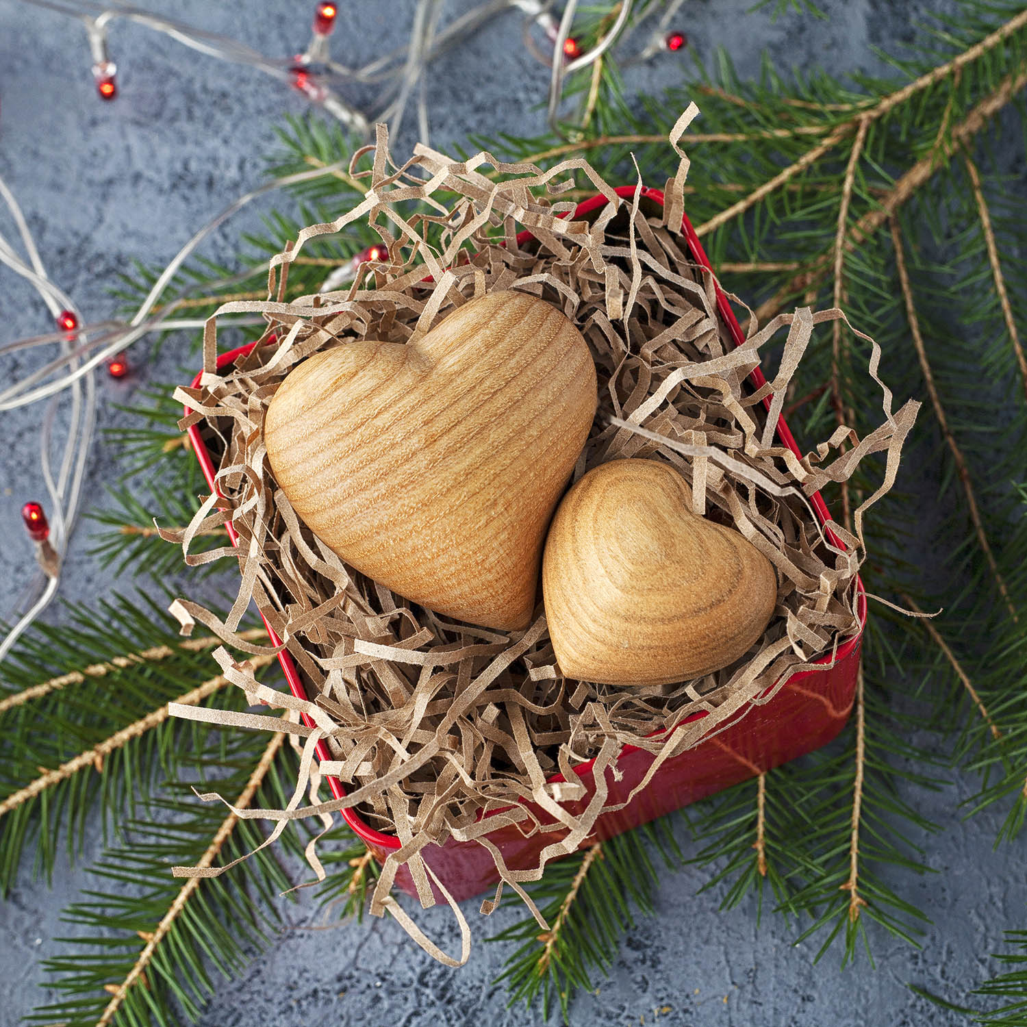 Two wooden hearts in a box on a grey background.