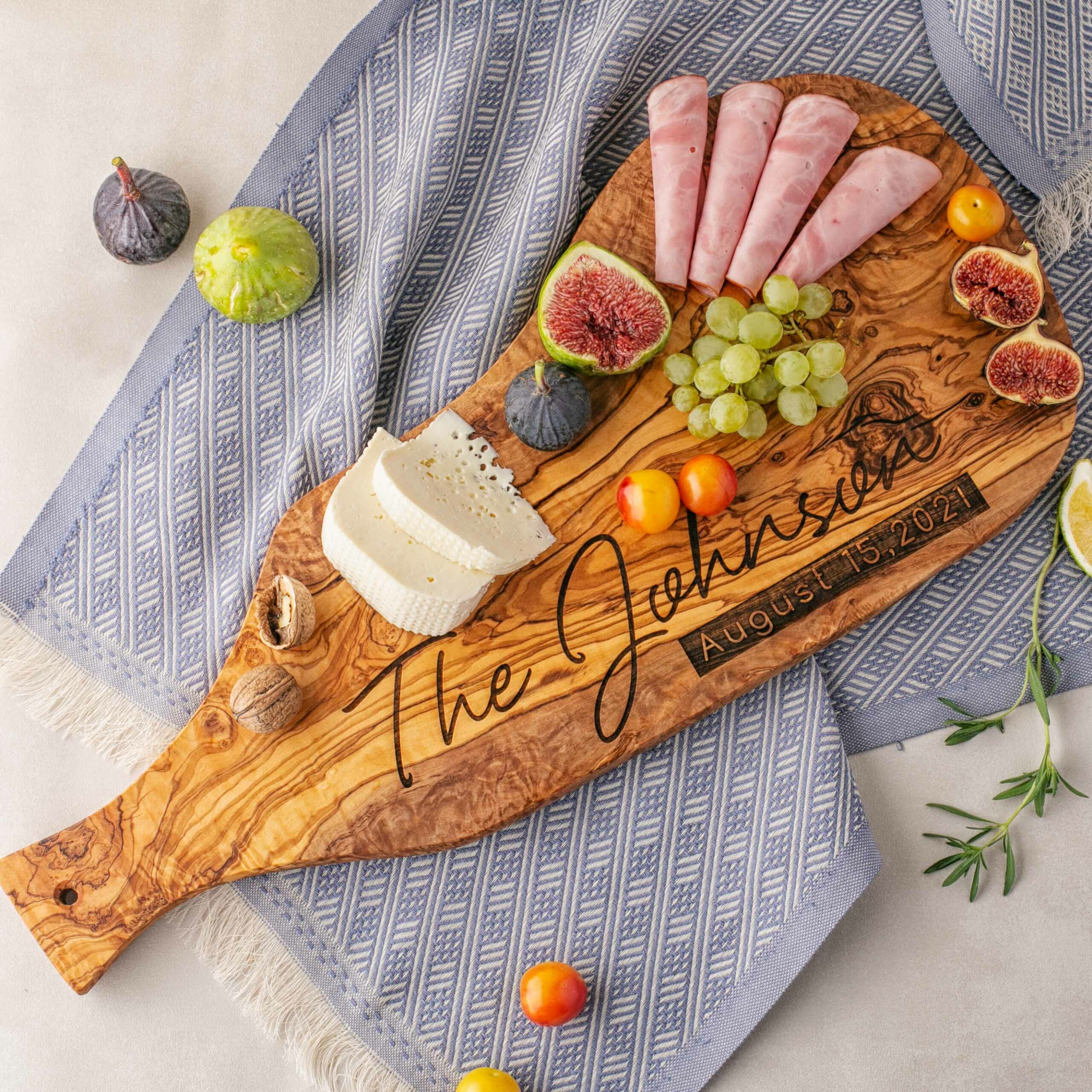 A Wooden Large serving board with figs, grapes and olives.