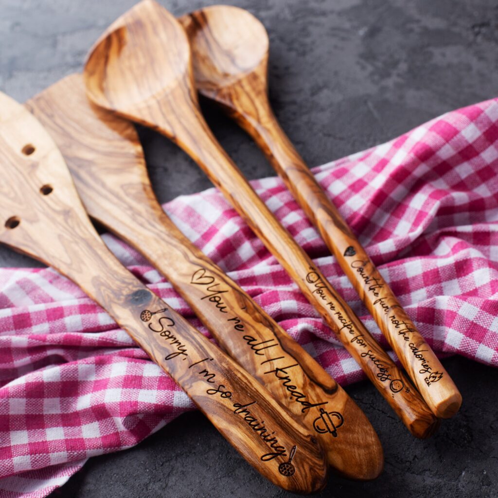 set of four wooden spoons with engraved names on them.