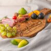 A Personalized Olive Wood Serving Charcuterie Board with fruit on it.