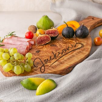 A Personalized Olive Wood Serving Charcuterie Board with fruit on it.