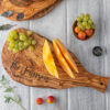 A Personalized Olive Wood Serving Charcuterie Board – 15″ with fruit and grapes on it.