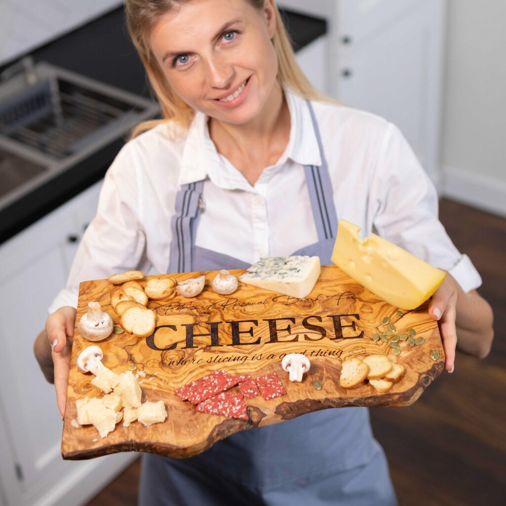 A woman is holding a cheese board in front of a kitchen.
