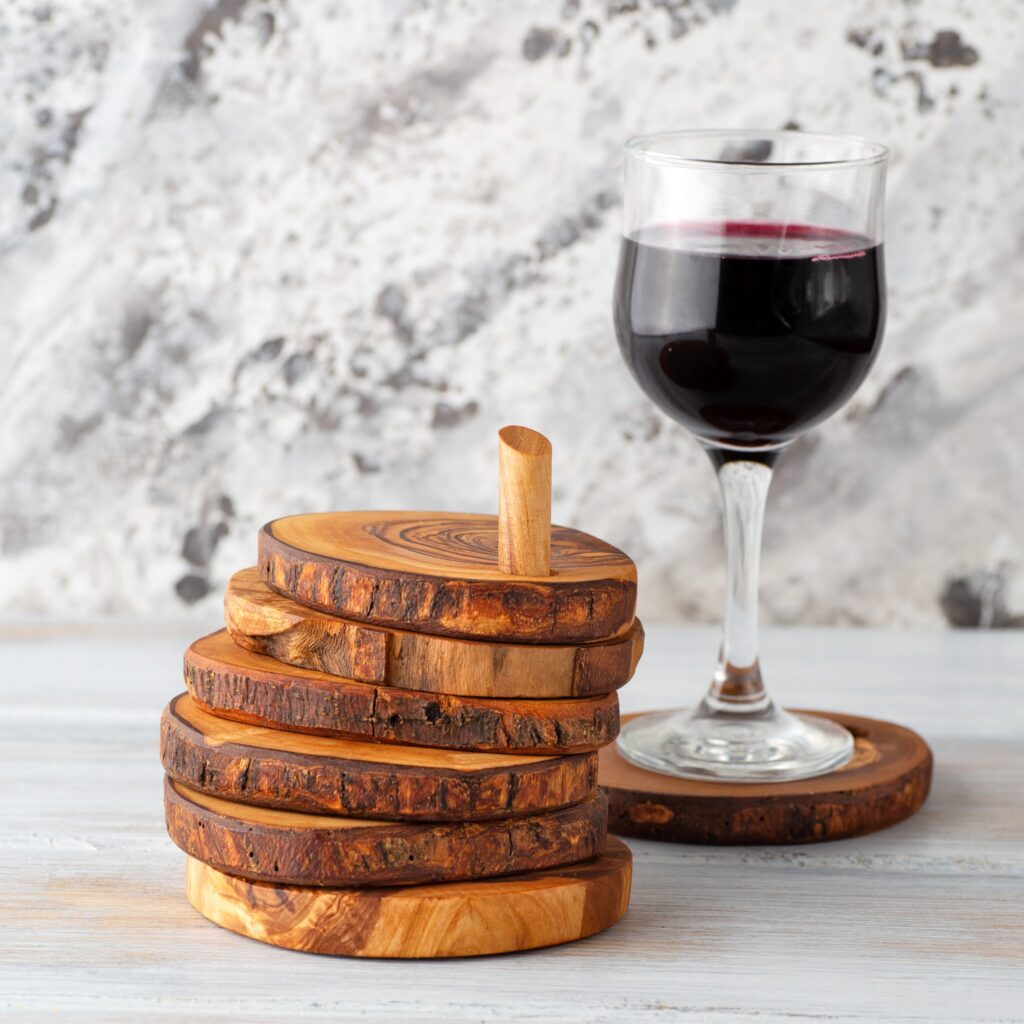 A wooden coaster with a glass of wine next to it.