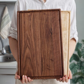 A woman holding up a wooden cutting board.