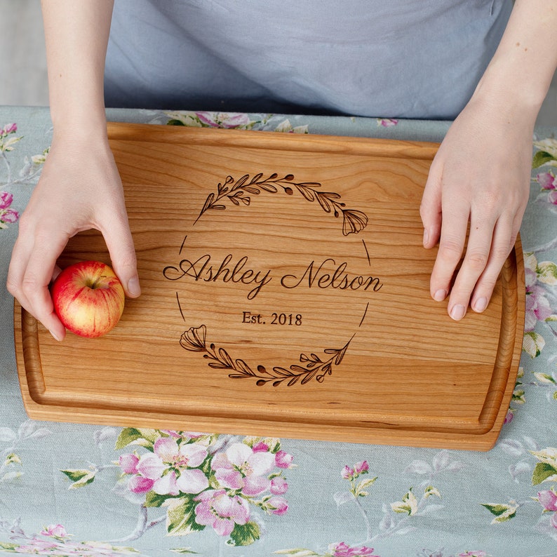 A woman is holding an apple on a wooden cutting board.