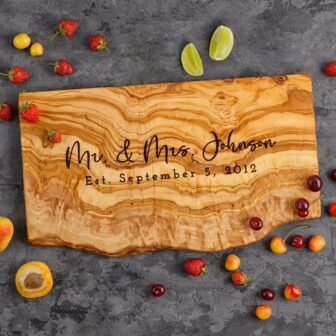 Personalized live edge charcuterie board with engraving and laying on top of a kitchen counter.