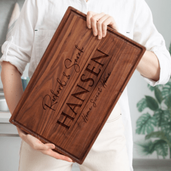 A woman is holding up a Engraved Wooden Cutting Board as Wedding Couple gift