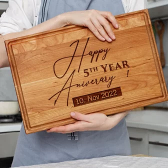 A woman holding up a Personalized Cherry Cutting Board that says happy 5th anniversary.