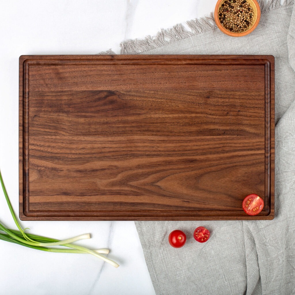 A walnut cutting board with tomatoes and onions.