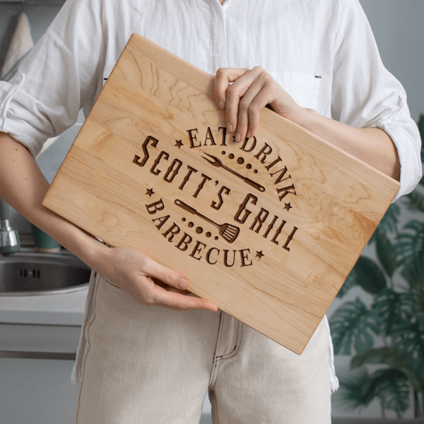 A woman holding a Grilling Gift Cutting Board that says Scott's grill.
