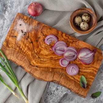 A Wood Live Edge Cutting Board with onions and garlic on it.