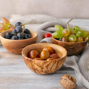 Three wooden bowls with grapes and walnuts.
