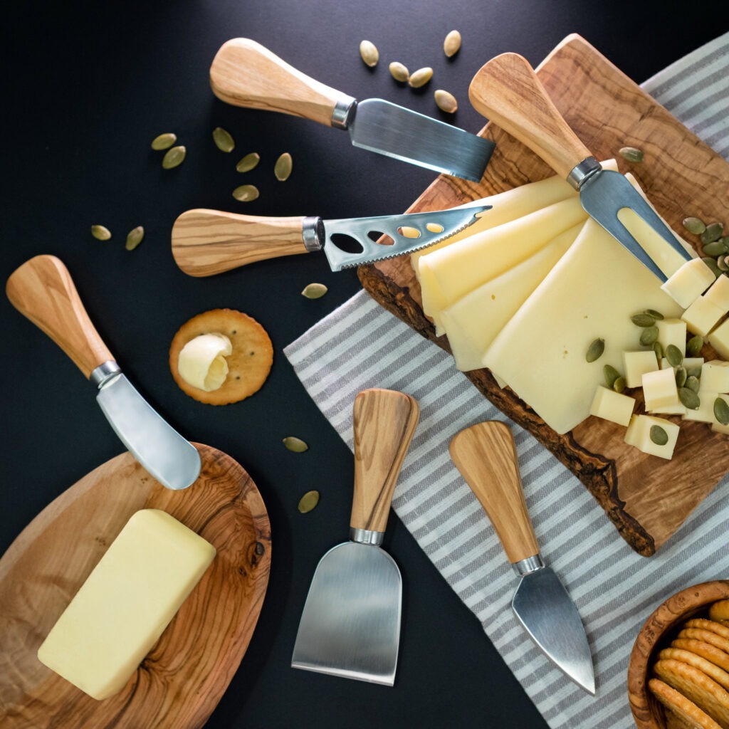 A wooden board with cheese, crackers, and a knife.