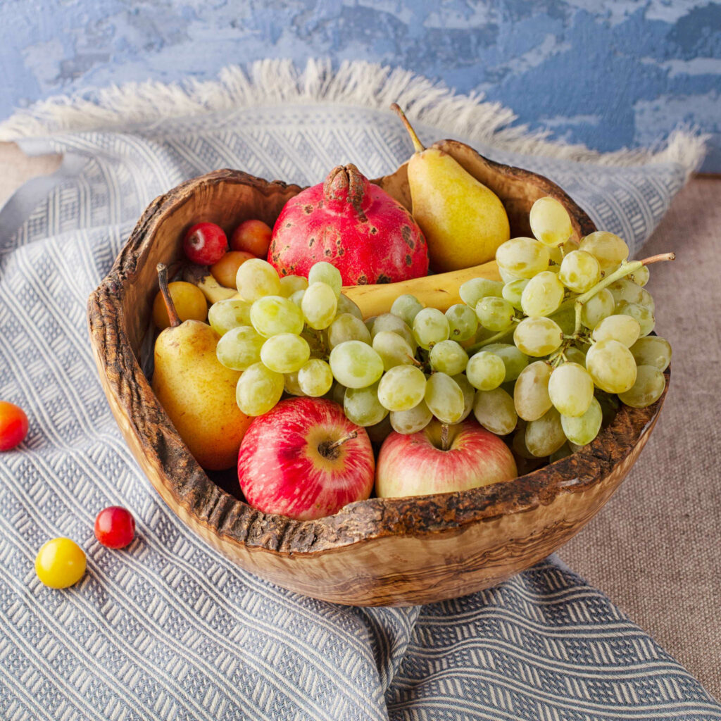 A Olive Wood Salad Bowl with Live Edge filled with fruit.