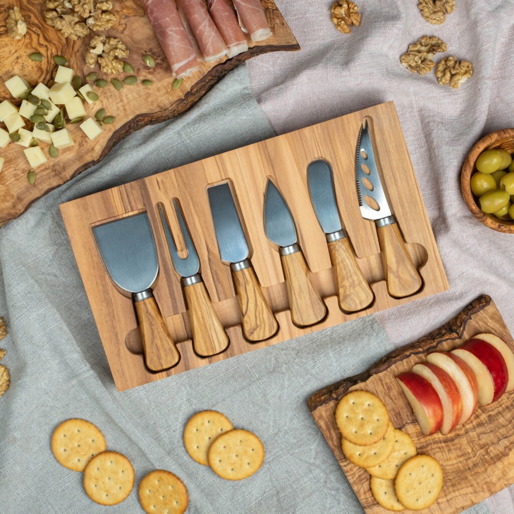 A wooden cheese board with cheese, crackers and olives.