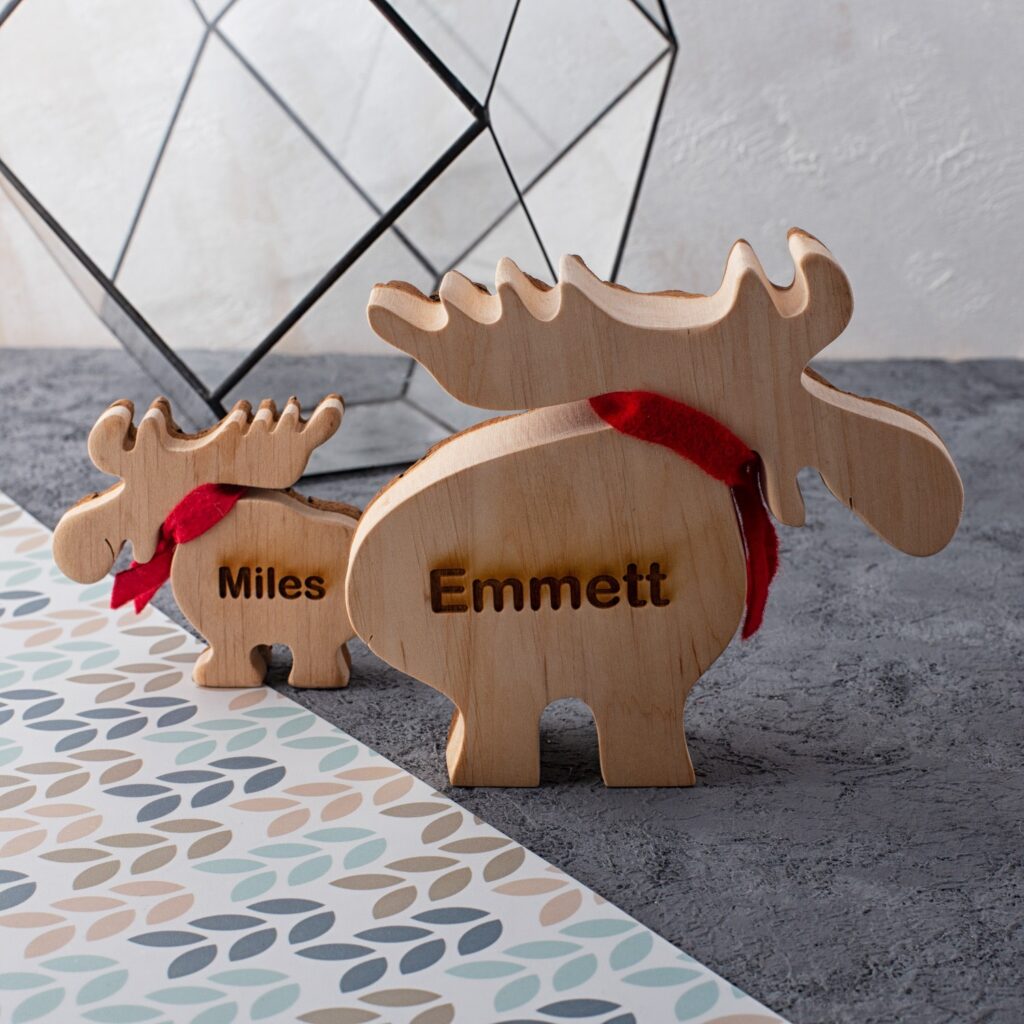 Two wooden moose figurines with the name emmett on them.