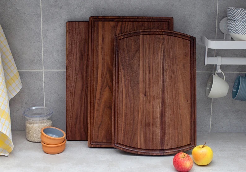 A walnut cutting board is sitting on a kitchen counter.