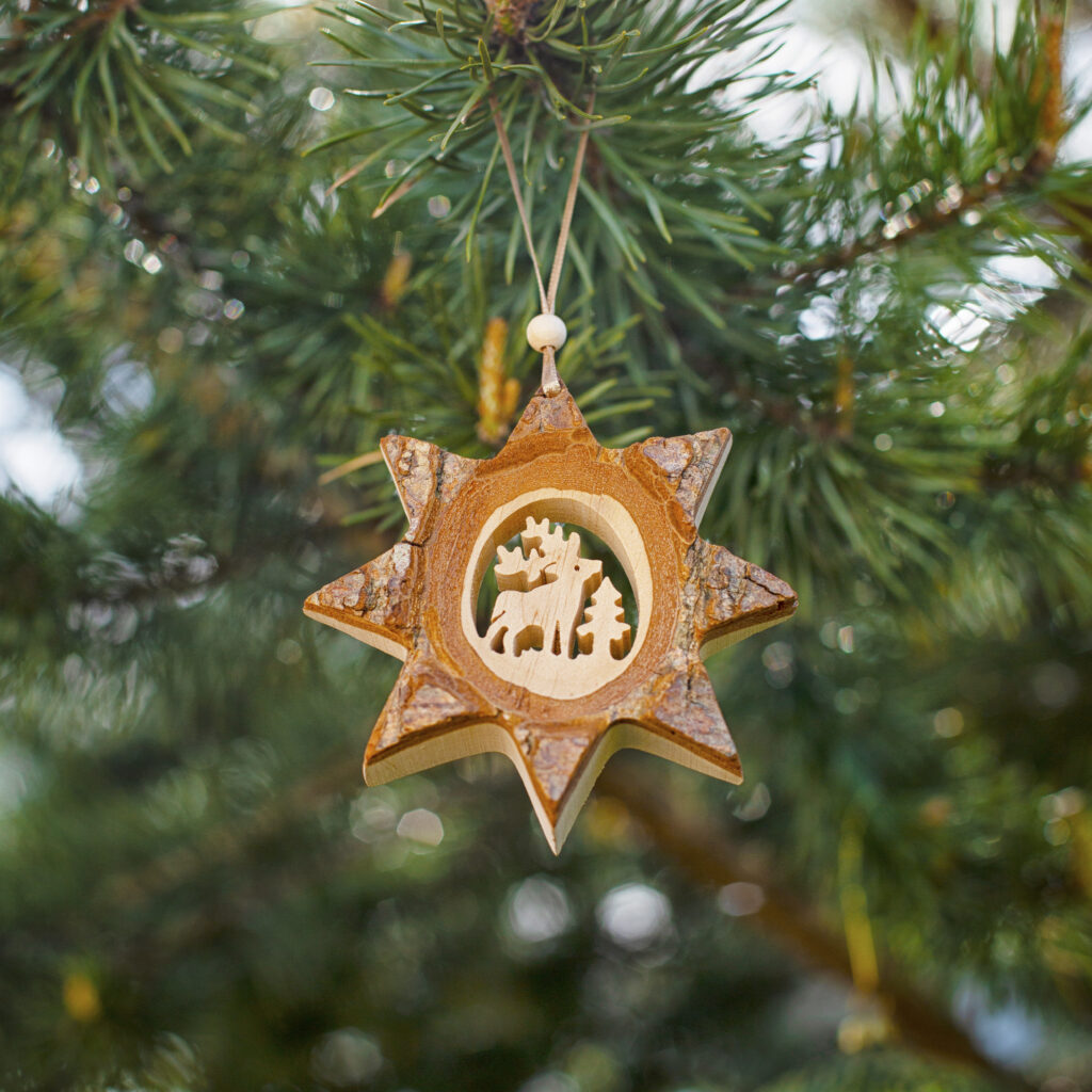 A wooden ornament hangs on a Christmas tree.