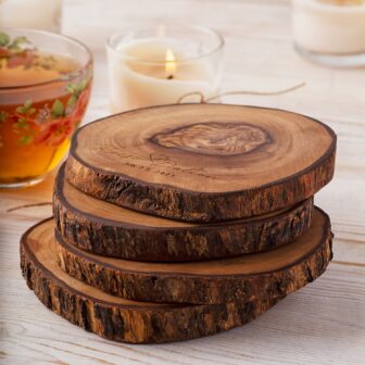 Four Wooden Engraved Round Coasters Set on a table next to a cup of tea.