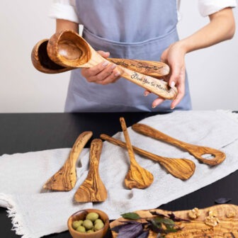 A woman holding Personalized Wooden Ladle and olives on a table.