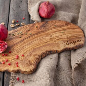 Personalized Olive Wood Charcuterie Board with pomegranates and pomegranate seeds.