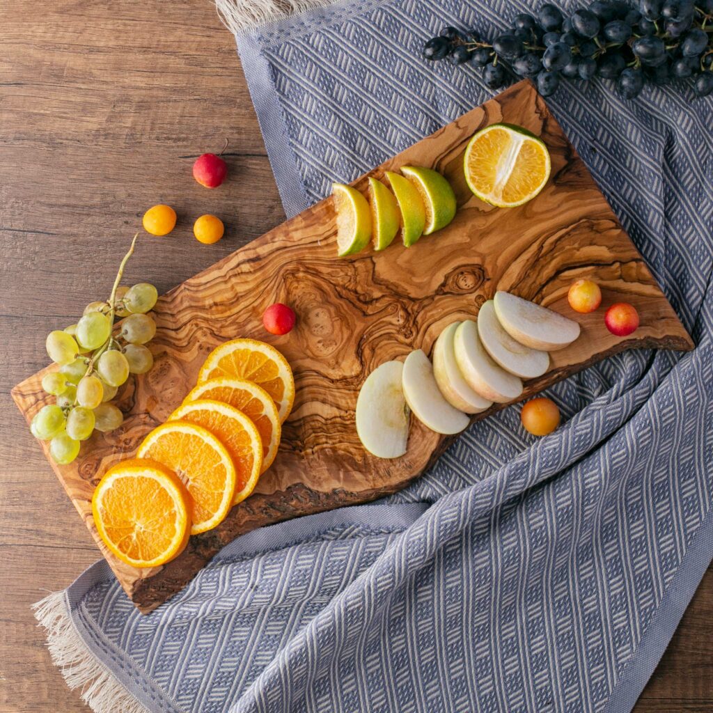A Wood Live Edge Cutting Board with oranges and grapes on it.