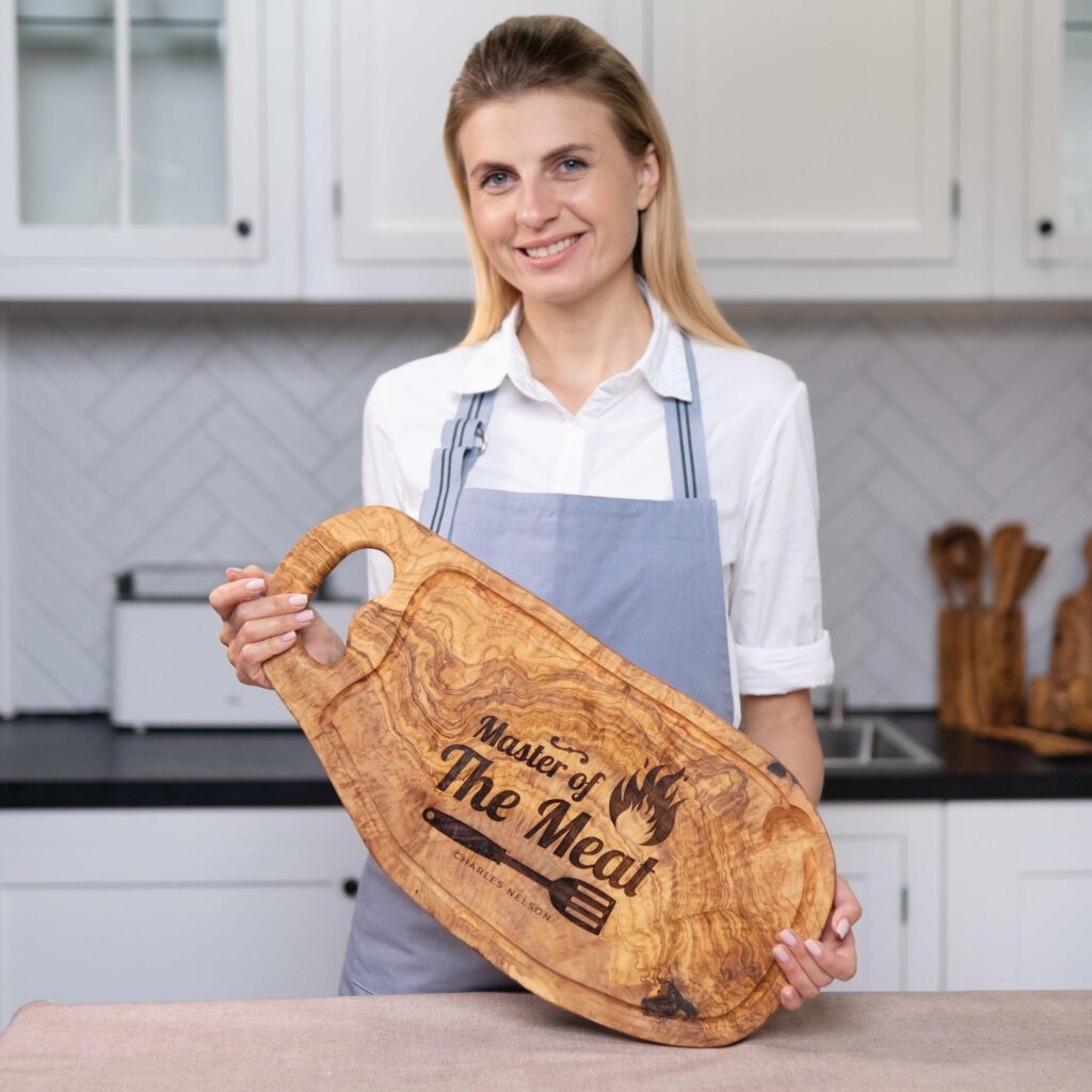 A woman in an apron holding a Personalized BBQ Cutting Board Olive Wood.