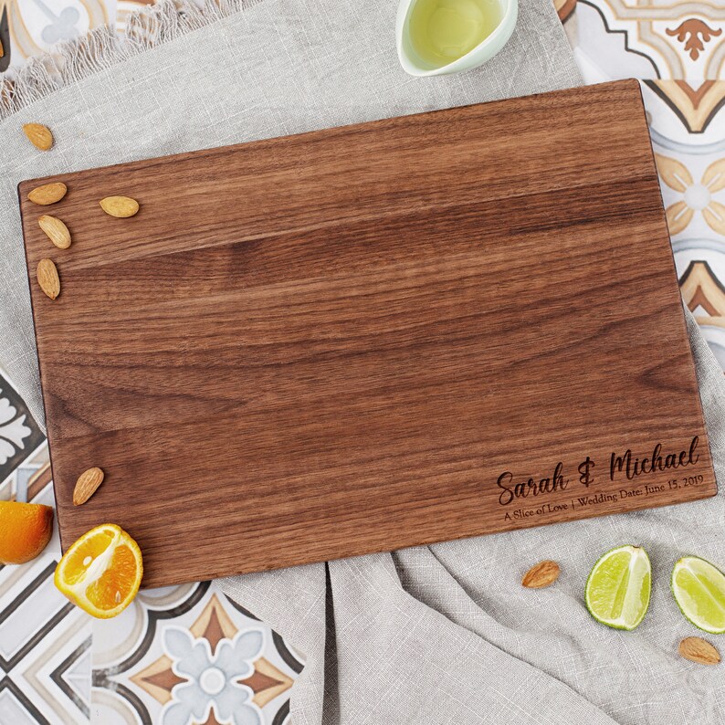 Engraved walnut cutting board with the couple's names in the bottom right corner.