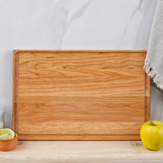 A wooden cutting board with an apple on it.
