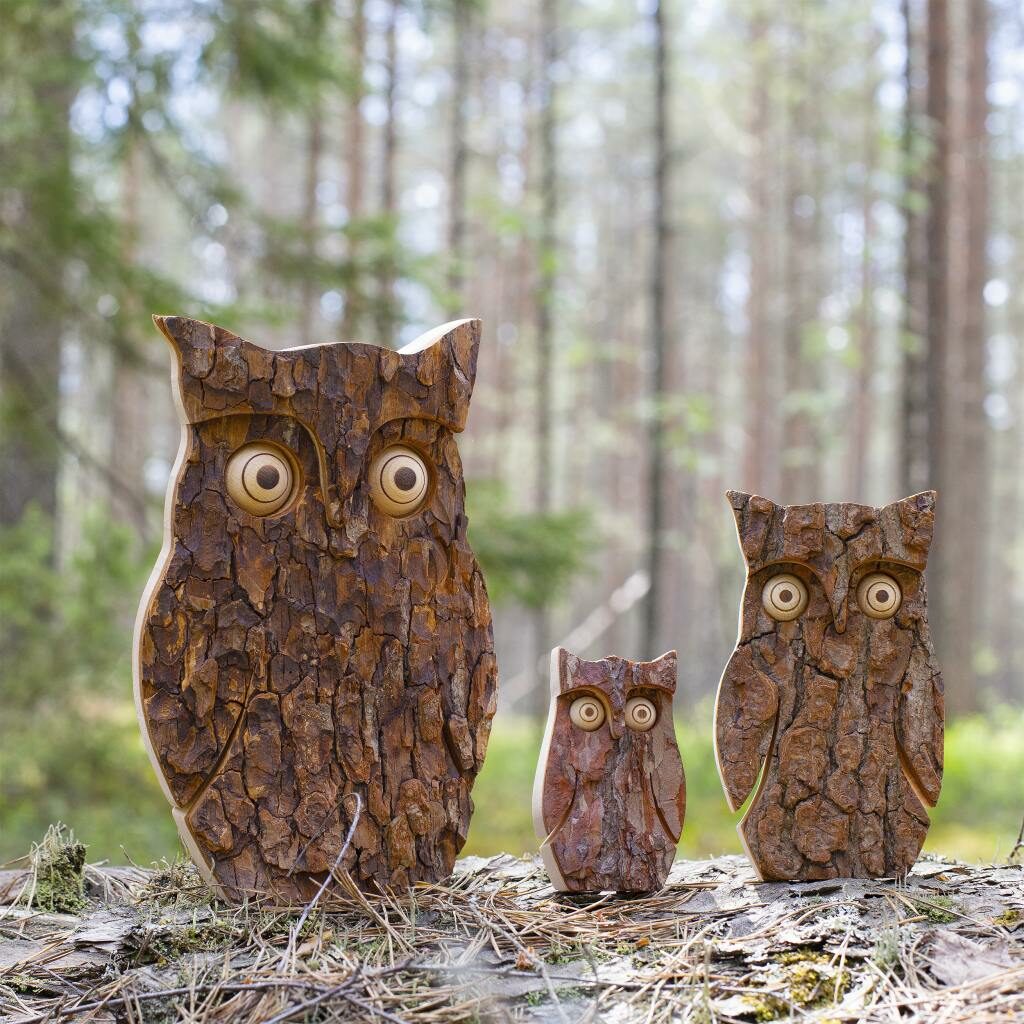 Three Wooden Owl Figurines for Home Decorations sitting on the ground in a forest.