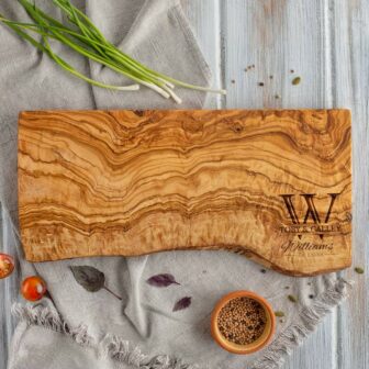 Olive wood live edge cutting board with monogram engraved in the bottom right corner.