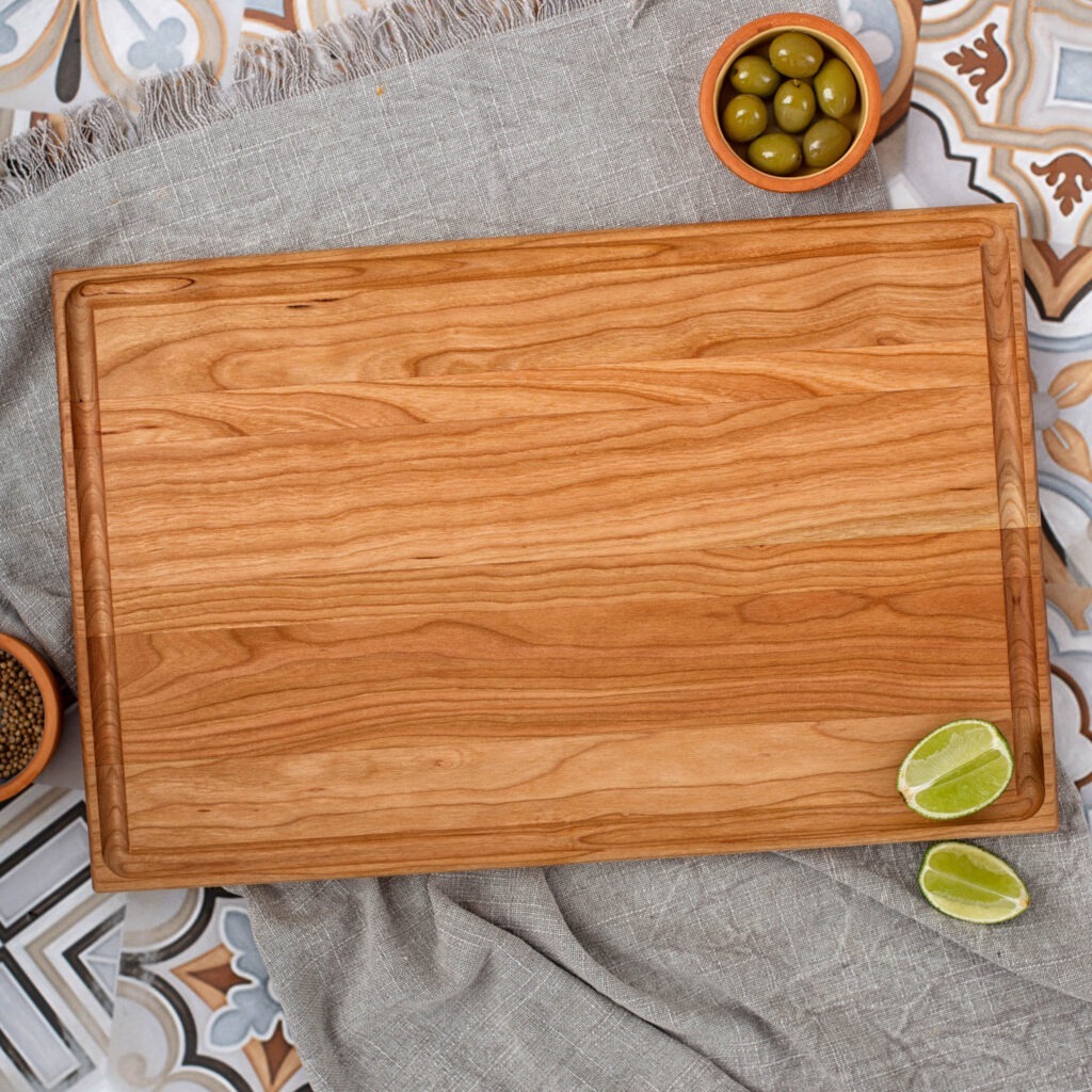A wooden cutting board with olives and limes on it.