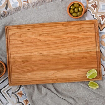 A wooden cutting board with olives and limes on it.