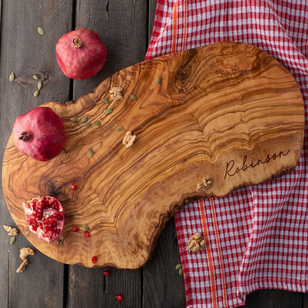Personalized Olive Wood Live Edge Board with pomegranates and pomegranate seeds.