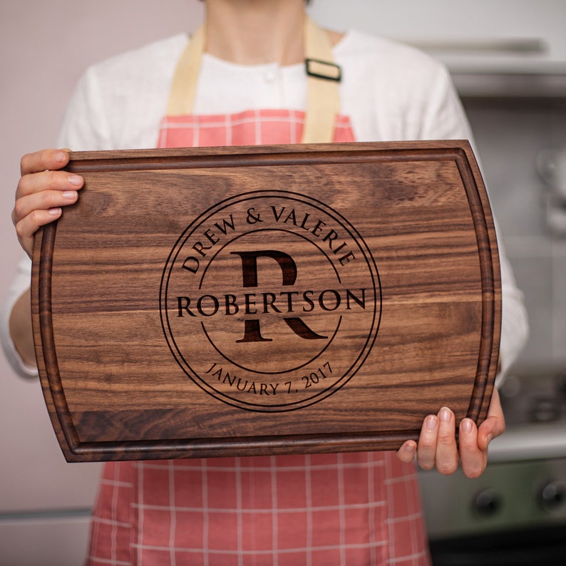 A woman holding up a Personalized Monogram Cutting Board with the name Robertson.