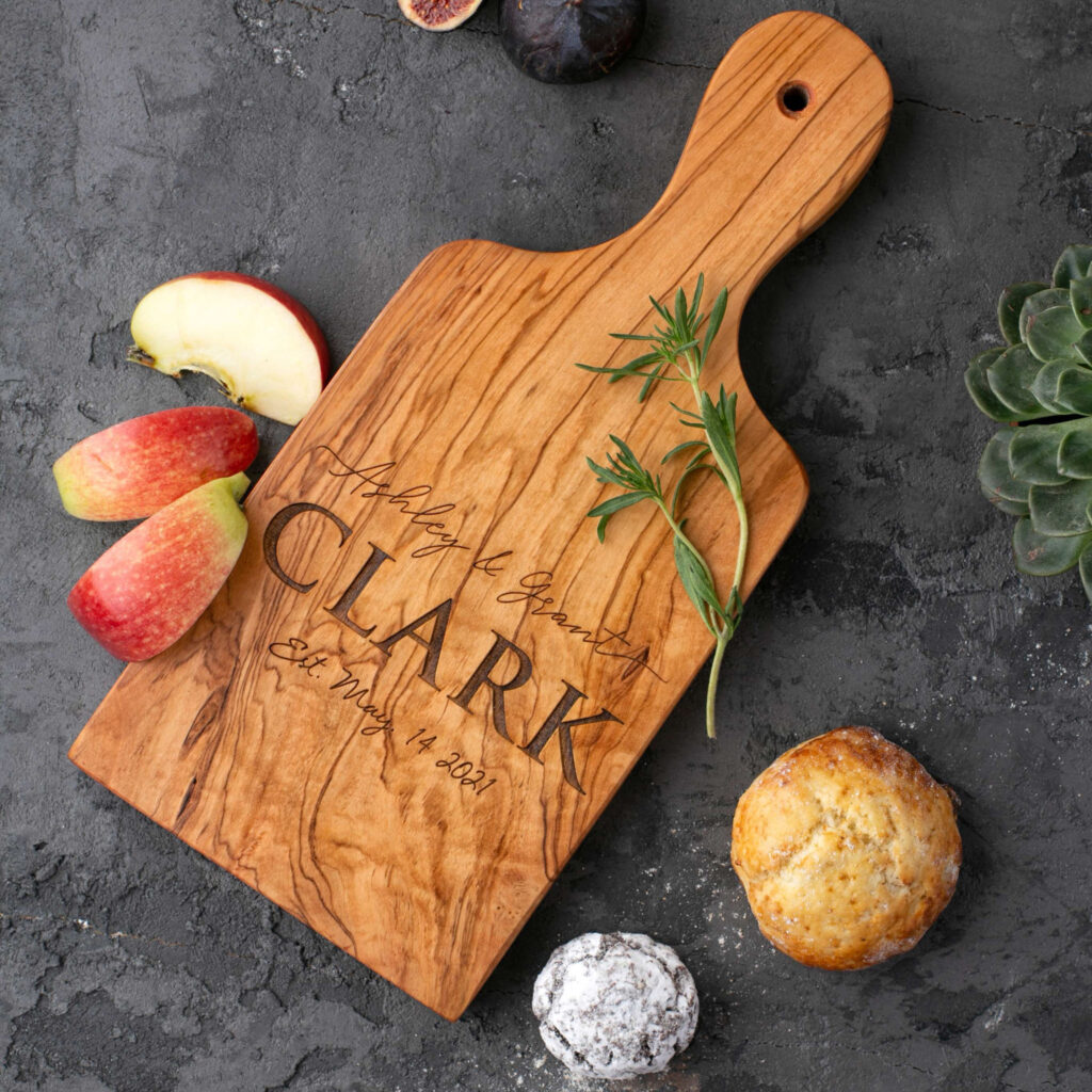 A Personalized Olive Wood Paddle Board with Handle with the word Clark on it.