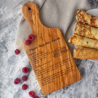 A Wooden Recipe Cutting Board with pancakes and raspberries on it.