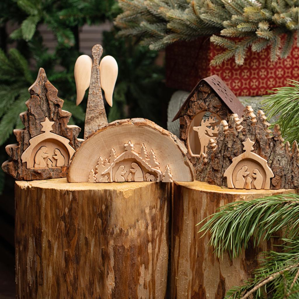 Several wooden nativity scenes, rustic candle holder and angel on top of a tree stump.
