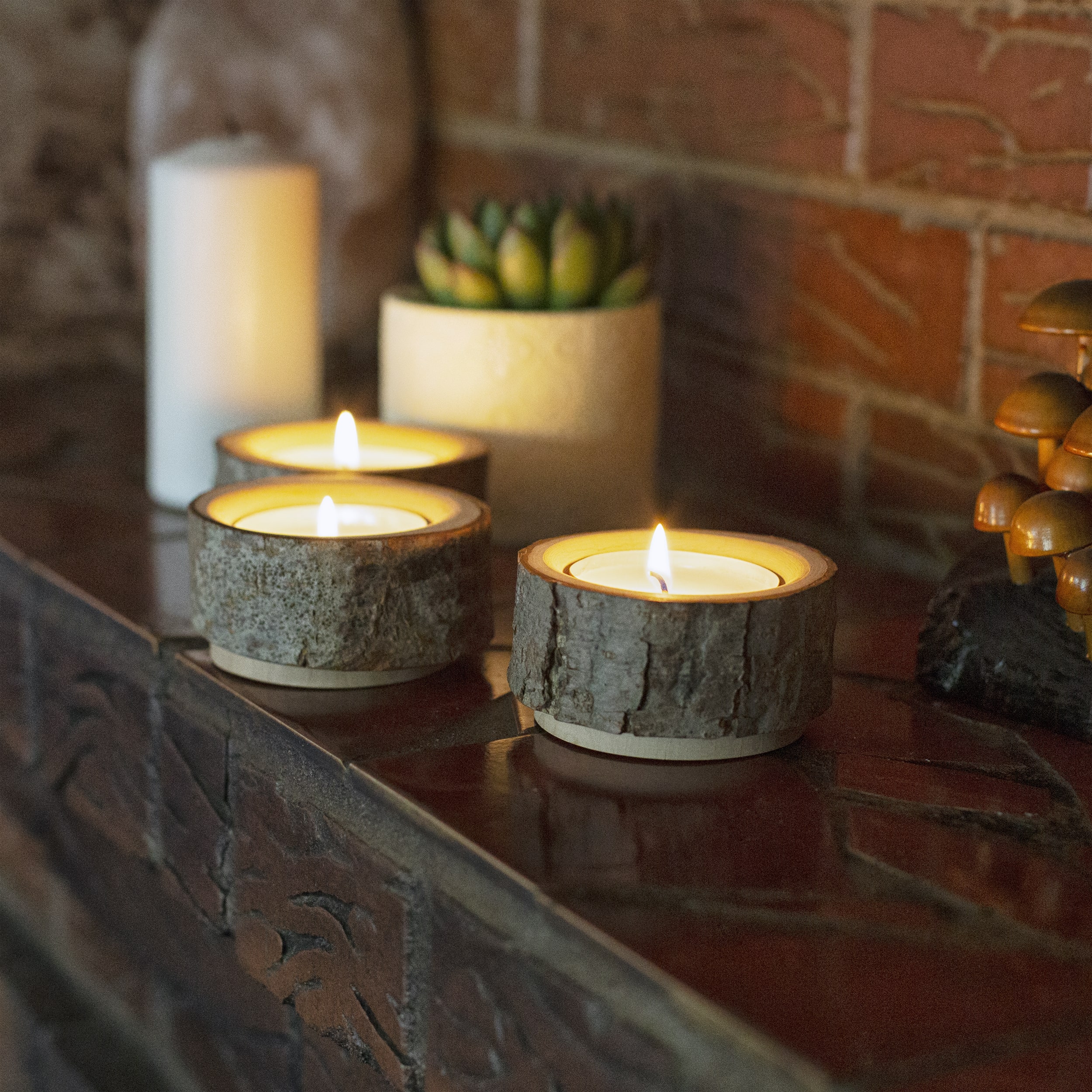 Three wood candles sitting on a mantle next to a cactus.