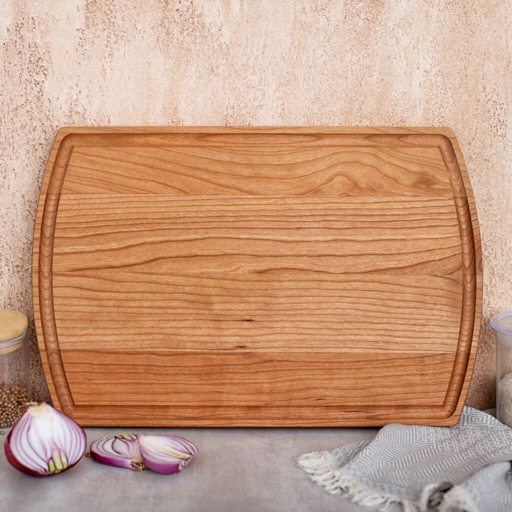 A wooden cutting board with onions and garlic on it.