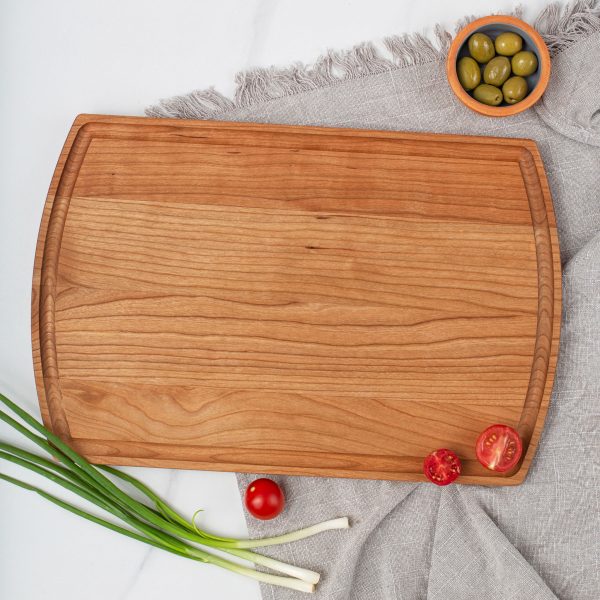 A wooden cutting board with olives and onions on it.